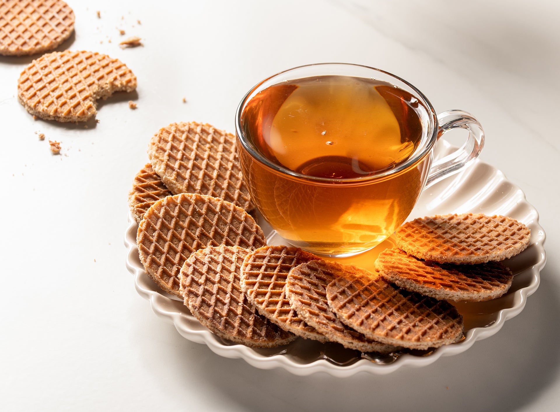 A cup of tea and Wonderen Stroopwafels 12 mini pack on a plate.