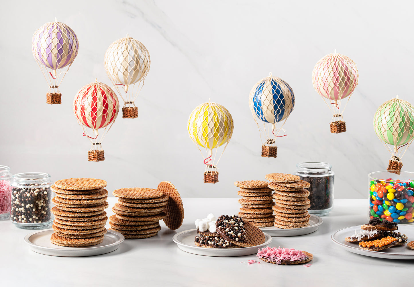 Hot air balloons and Dutch snacks on a table, including Wonderen Stroopwafels 12 mini pack.